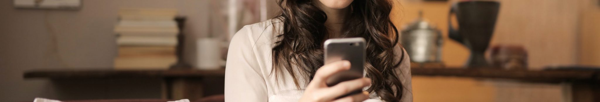 woman-sitting-on-sofa-while-looking-at-phone-with-laptop-on-920382